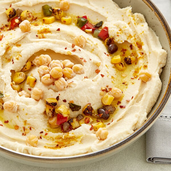 A bowl of hummus with chickpeas and spices on top.