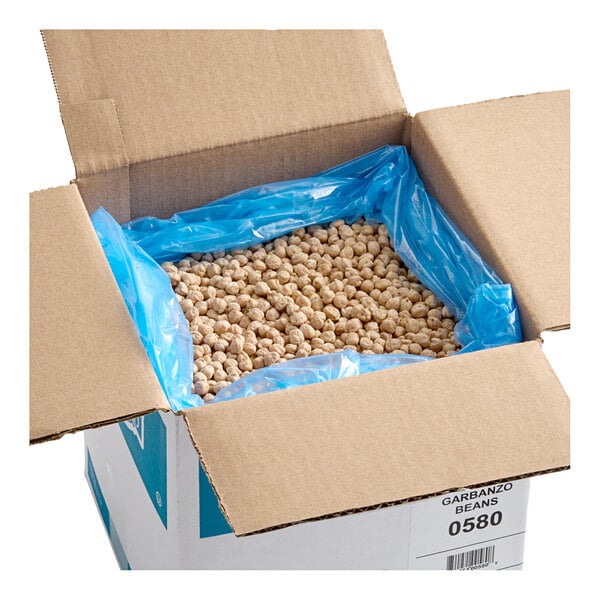 A large cardboard box lined with a blue plastic bag and filled with dried chickpeas (garbanzo beans).
