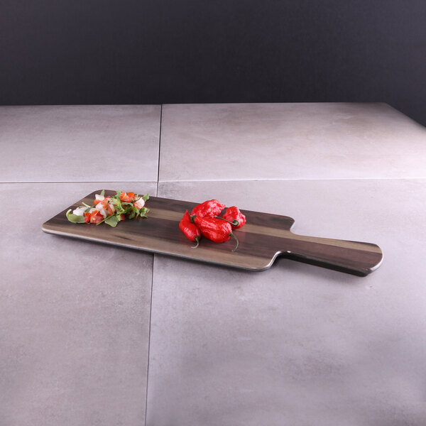 An Elite Global Solutions rectangular faux hickory wood serving board with red peppers on it.