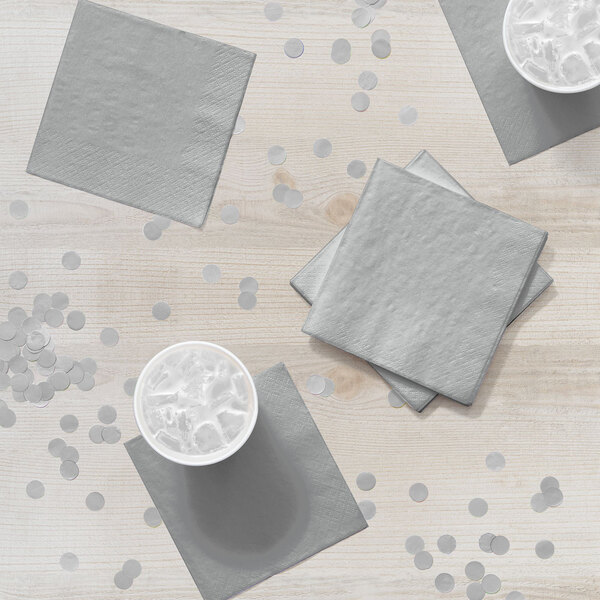 A stack of Shimmering Silver 2-ply beverage napkins on a table.