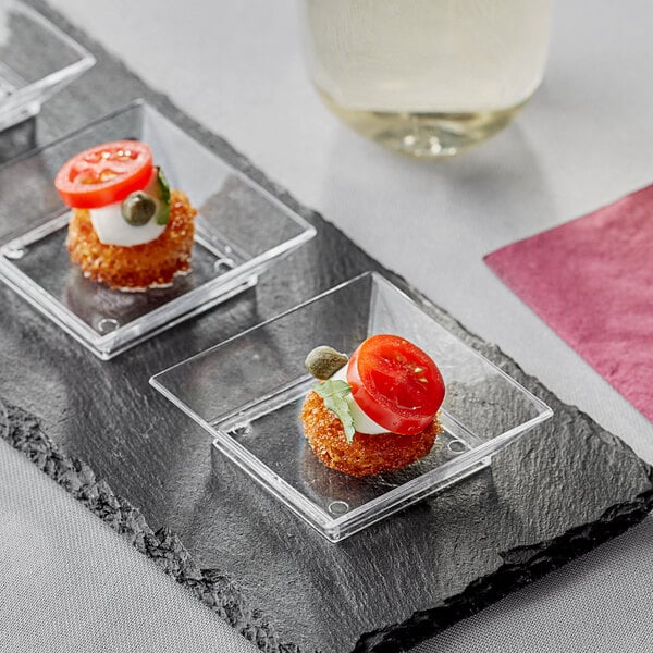 A group of Fineline clear disposable plastic trays with tomato and mozzarella on them on a table.