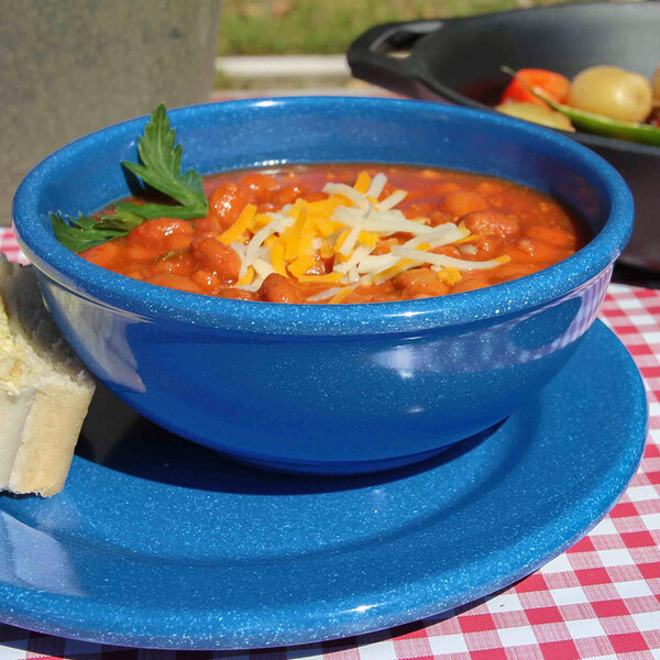 A blue speckled bowl of red bean soup with cheese and bread on a table.