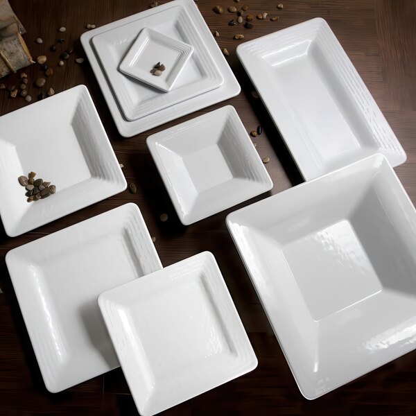 A stack of white square plates on a table.