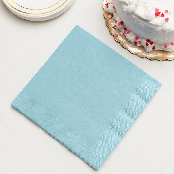 A pastel blue paper dinner napkin next to a white cake.