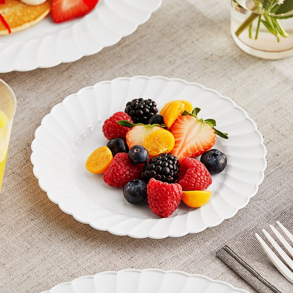 A WNA Comet white plastic plate with a slice of fruit on it.