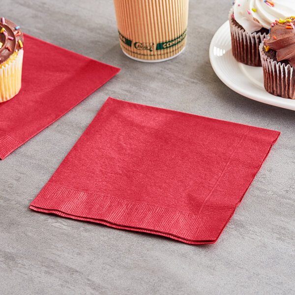 A red Creative Converting luncheon napkin with a cupcake on it.