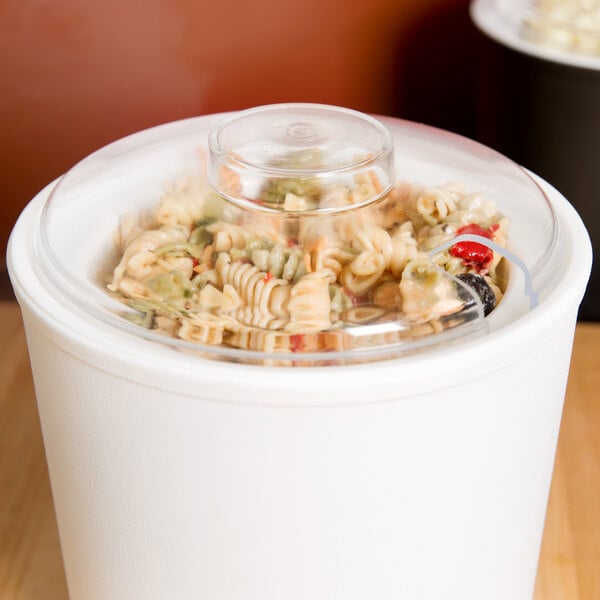 A Carlisle clear plastic lid with slots on a clear container of food.