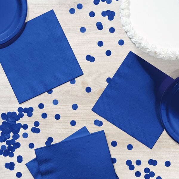 A table set with blue luncheon napkins and a blue polka dot paper plate.