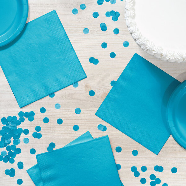 A table with blue napkins and confetti.