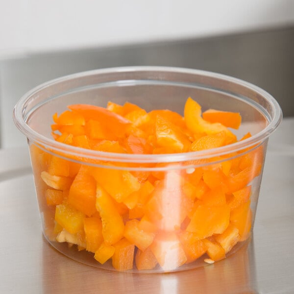 A Choice plastic deli container filled with chopped orange peppers.