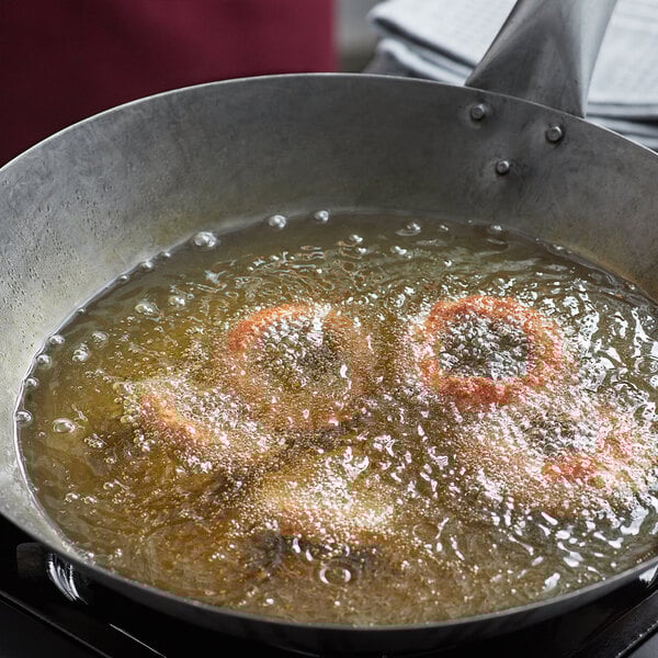 A frying pan of onion rings cooking in cottonseed oil.