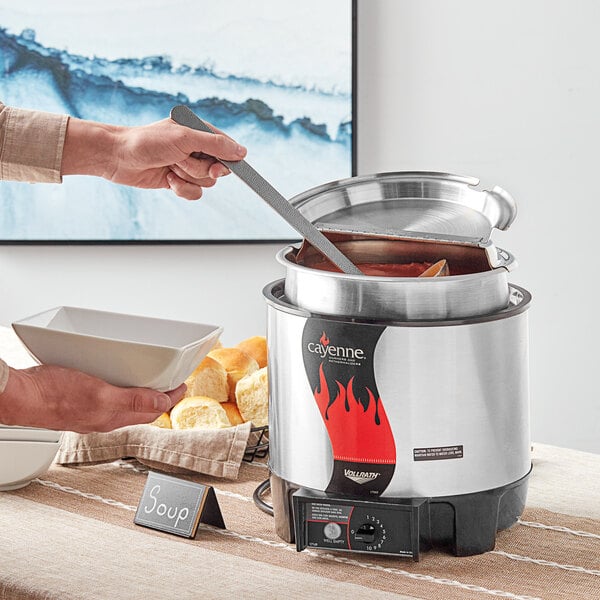 A person cooking soup in a Vollrath countertop soup warmer.