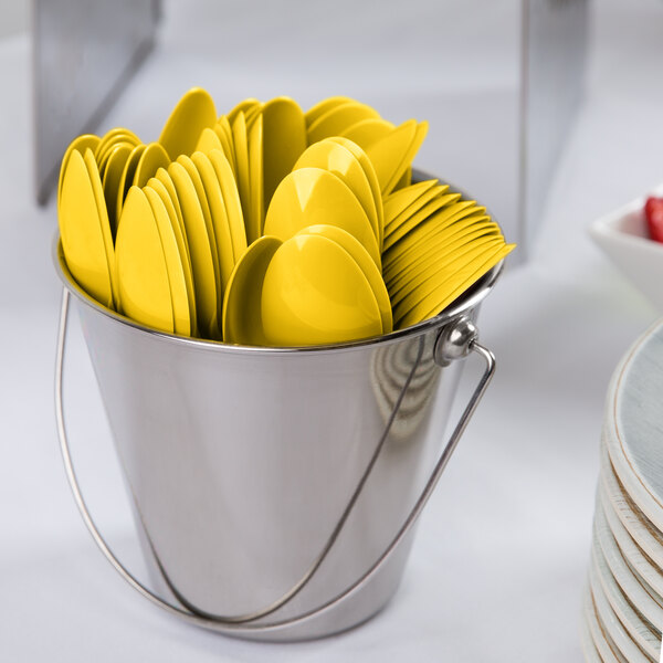 A bucket of Creative Converting School Bus Yellow plastic spoons.