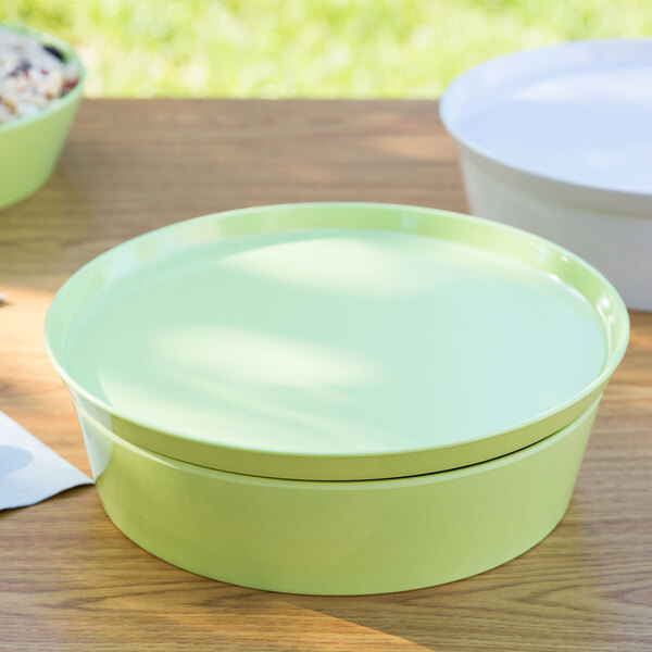 A lime green melamine bowl with a lid on a wood table.