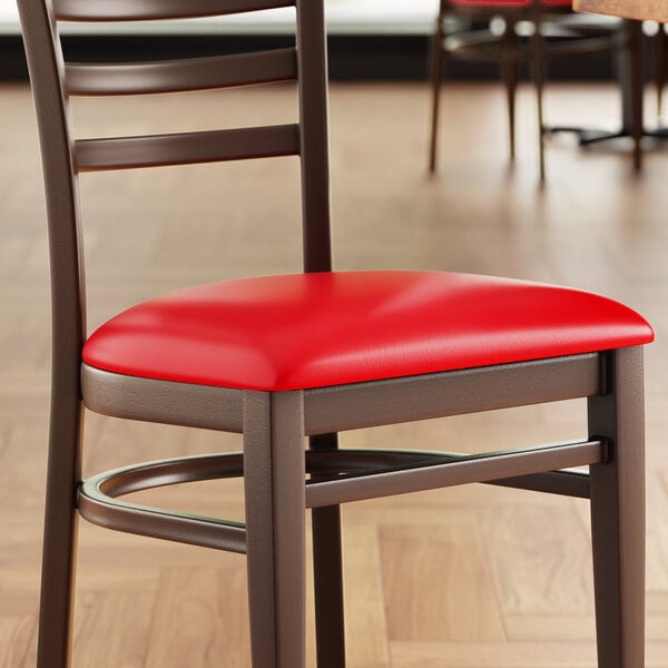 A Lancaster Table & Seating red vinyl padded chair seat on a chair in a restaurant dining area.