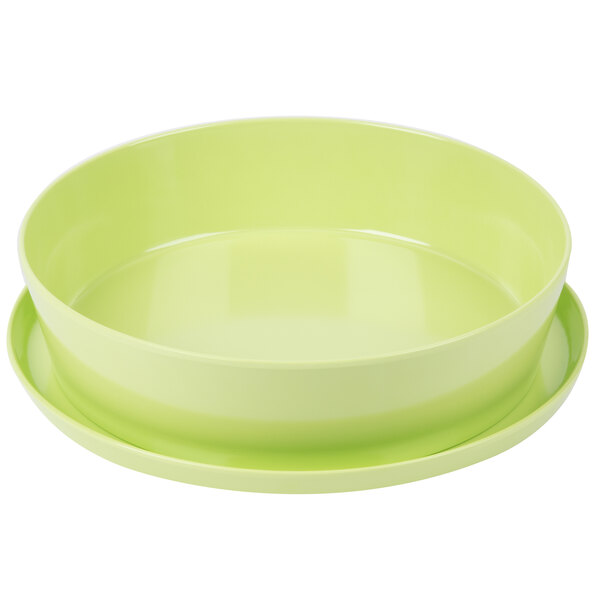 A lime green melamine bowl with a green lid and two plates on top.