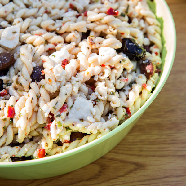 A lime melamine bowl of pasta with olives and cheese.