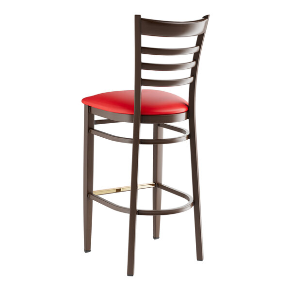 A Lancaster Table & Seating red metal ladder back bar stool with a red vinyl seat.