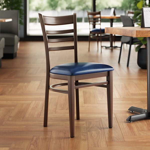 A Lancaster Table & Seating Spartan Series metal ladder back chair with dark walnut wood grain finish and navy vinyl seat.