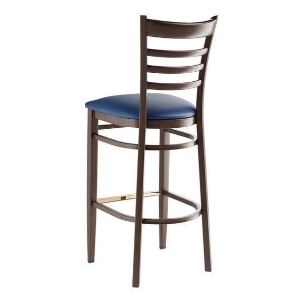 A metal ladder back bar stool with a dark walnut wood grain finish and a navy vinyl seat.