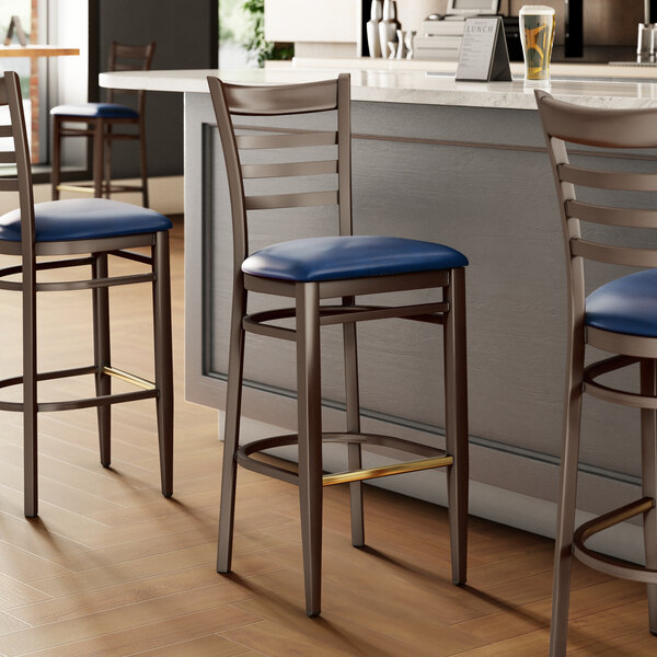 A metal bar stool with a dark walnut wood grain finish, ladder back design, and a navy vinyl seat.