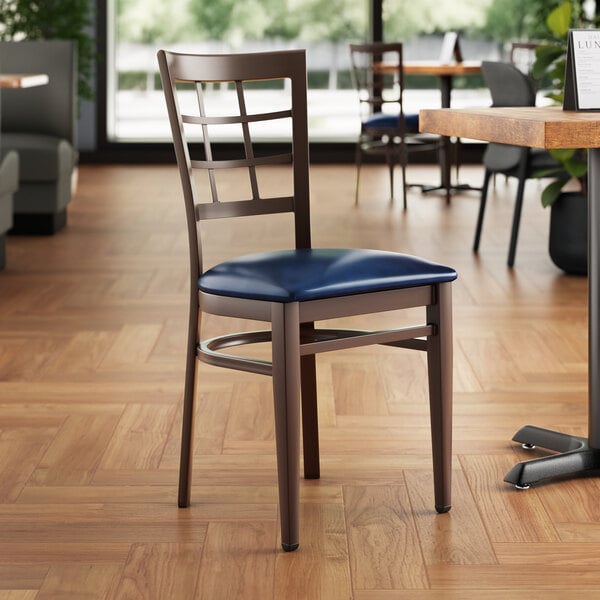 A Lancaster Table & Seating Spartan Series metal chair with a dark walnut wood grain finish and navy vinyl seat.