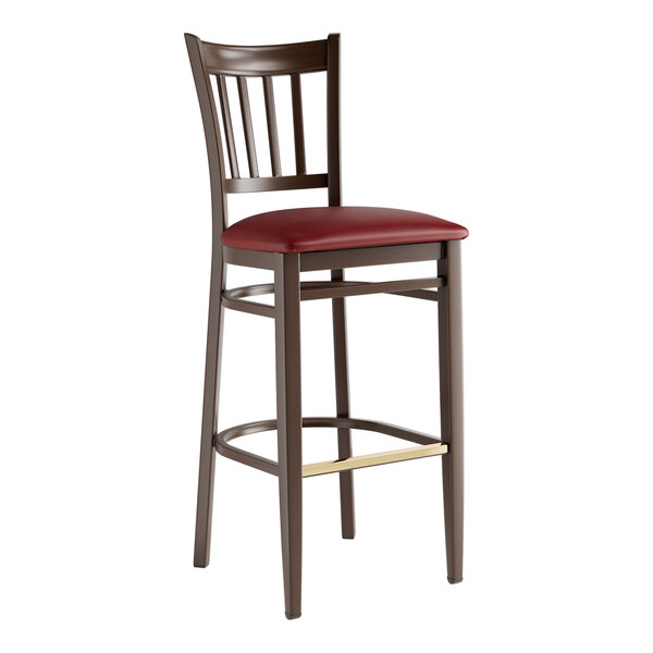 A Lancaster Table & Seating Spartan Series metal slat back bar stool with dark walnut wood grain finish and burgundy vinyl seat.