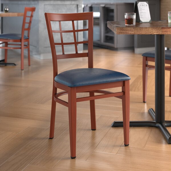 A Lancaster Table & Seating Spartan Series metal window back chair with a navy vinyl seat on a table in a restaurant dining area.