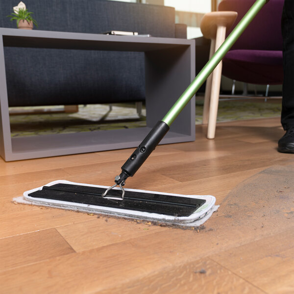 A rectangular duster sheet attached to a mop being used to clean a hardwood floor.