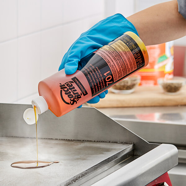 A person in blue gloves pouring 3M Liquid Griddle Quick Clean onto a grill.