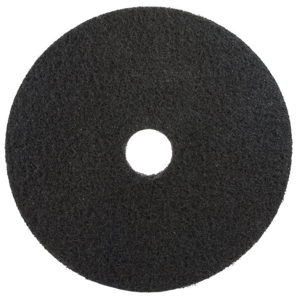 A 3M black circular floor pad with a hole in the middle.