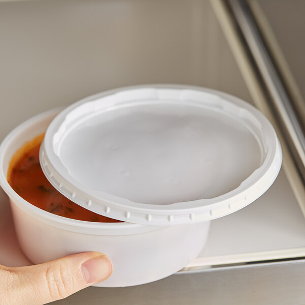 A hand holding a Choice white plastic deli container with a lid.