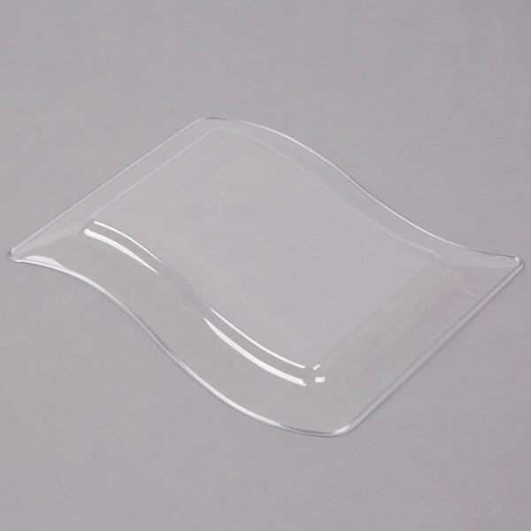 A clear plastic dessert plate with a wavy edge.