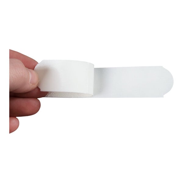 A hand holding a strip of white adhesive tape with a rounded end.