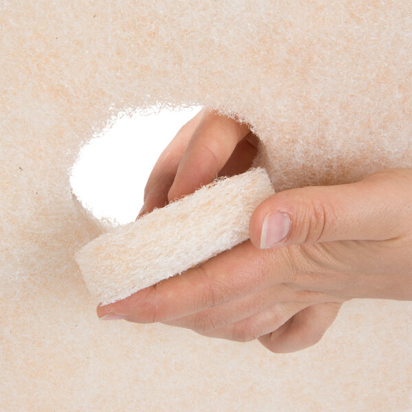 A hand holding a white 3M burnishing floor pad.