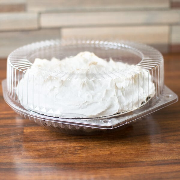 A Polar Pak clear plastic container with a high dome lid holding a cake with white frosting.