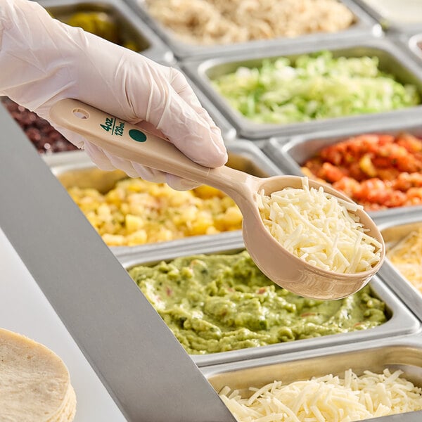 A person holding a Carlisle Measure Misers short handle portion spoon over food.