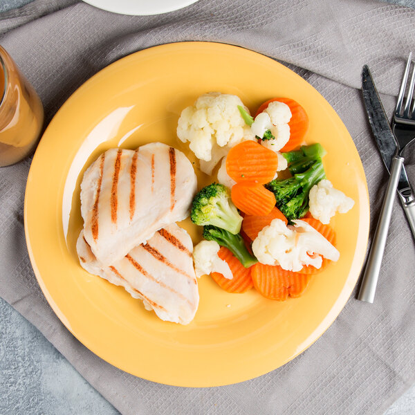 A plate of food with chicken and vegetables on a GET Diamond Mardi Gras Tropical Yellow melamine plate.