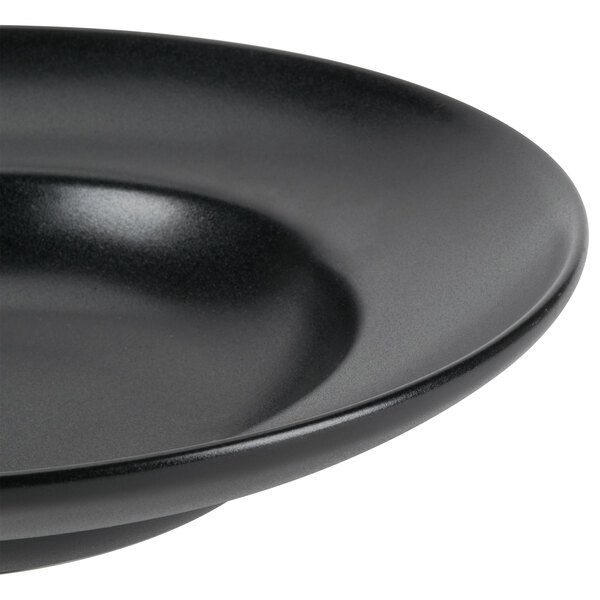 A close-up of a black Hall China Mediterranean pasta bowl.