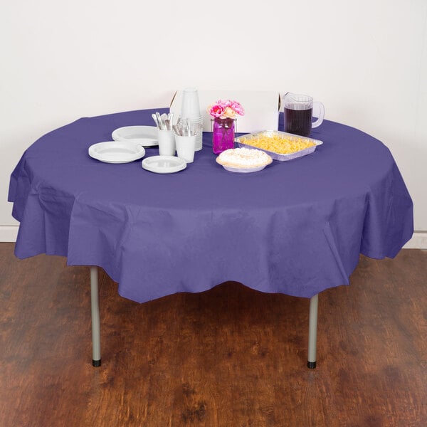 A table with a purple Creative Converting OctyRound tablecloth, plates, and utensils.