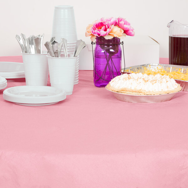A table set with Classic Pink OctyRound table cover, plates, and utensils.
