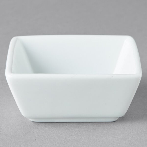 A white square Libbey porcelain bowl on a gray surface.