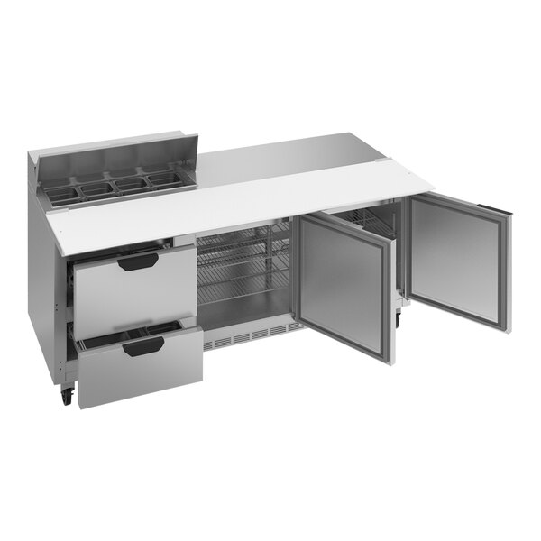 A stainless steel counter top with open doors and two drawers.