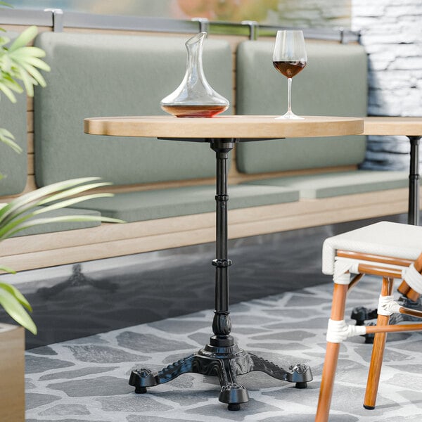 A FLAT Tech black restaurant table base with a glass and decanter on top.