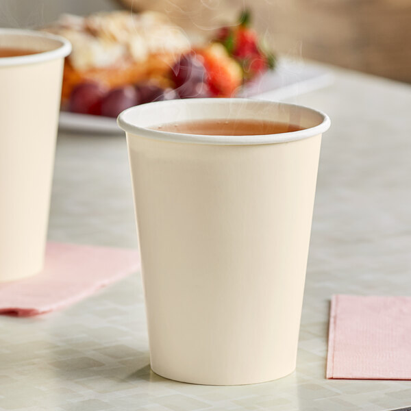 Two ivory Creative Converting paper cups with a hot drink in one of them.