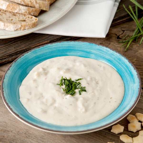 A Carlisle Aqua Melamine rimmed soup bowl filled with soup with chives on top.