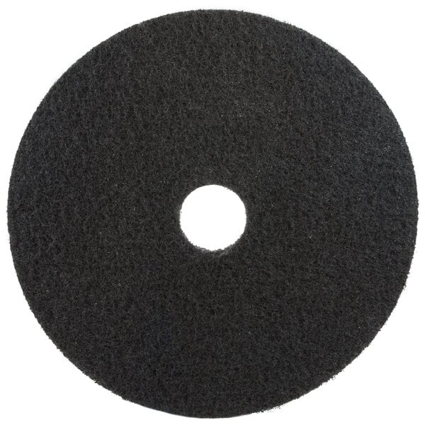 A 3M black circular floor pad with a hole in the center.