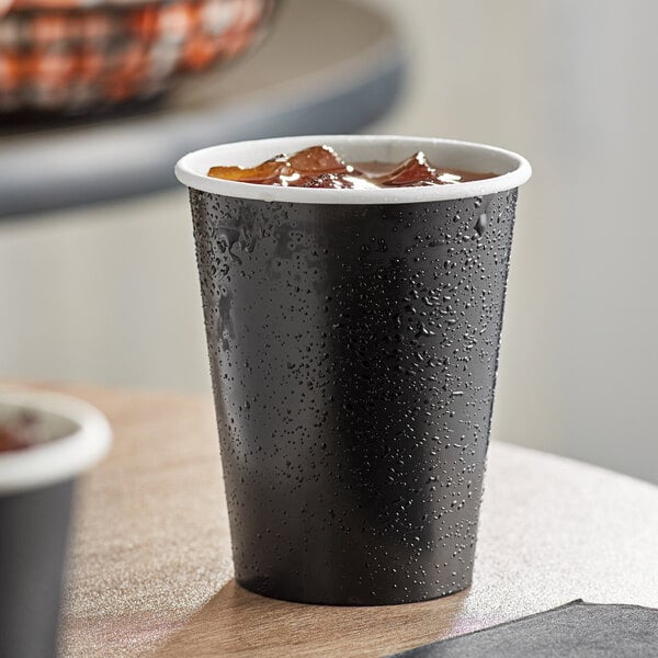 A pack of two black Creative Converting paper cups with ice and drinks.