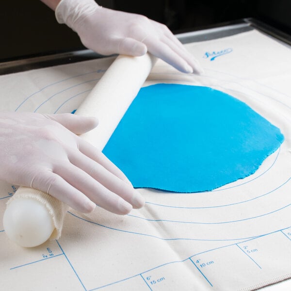 blue fondant being rolled flat on a measuring pad