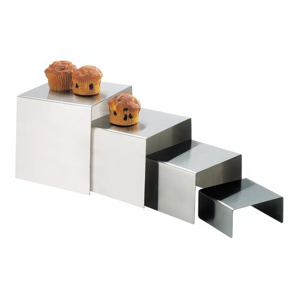 A group of muffins on a metal cube riser.